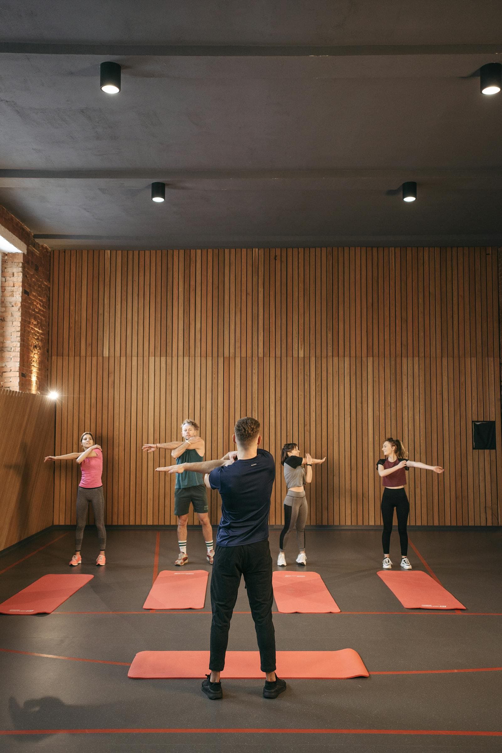 Cours collectif dans la salle du club, le groupe suit le mouvement sur tapis