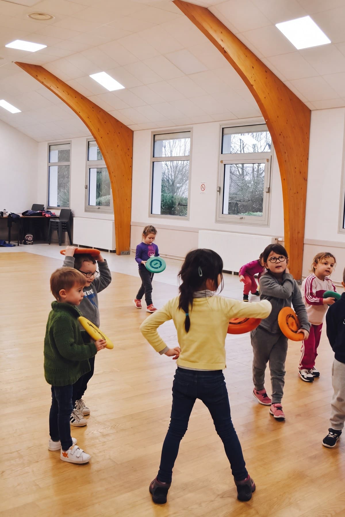 Des enfants debout dans la salle avec des anneaux de lancer colorés à la main.