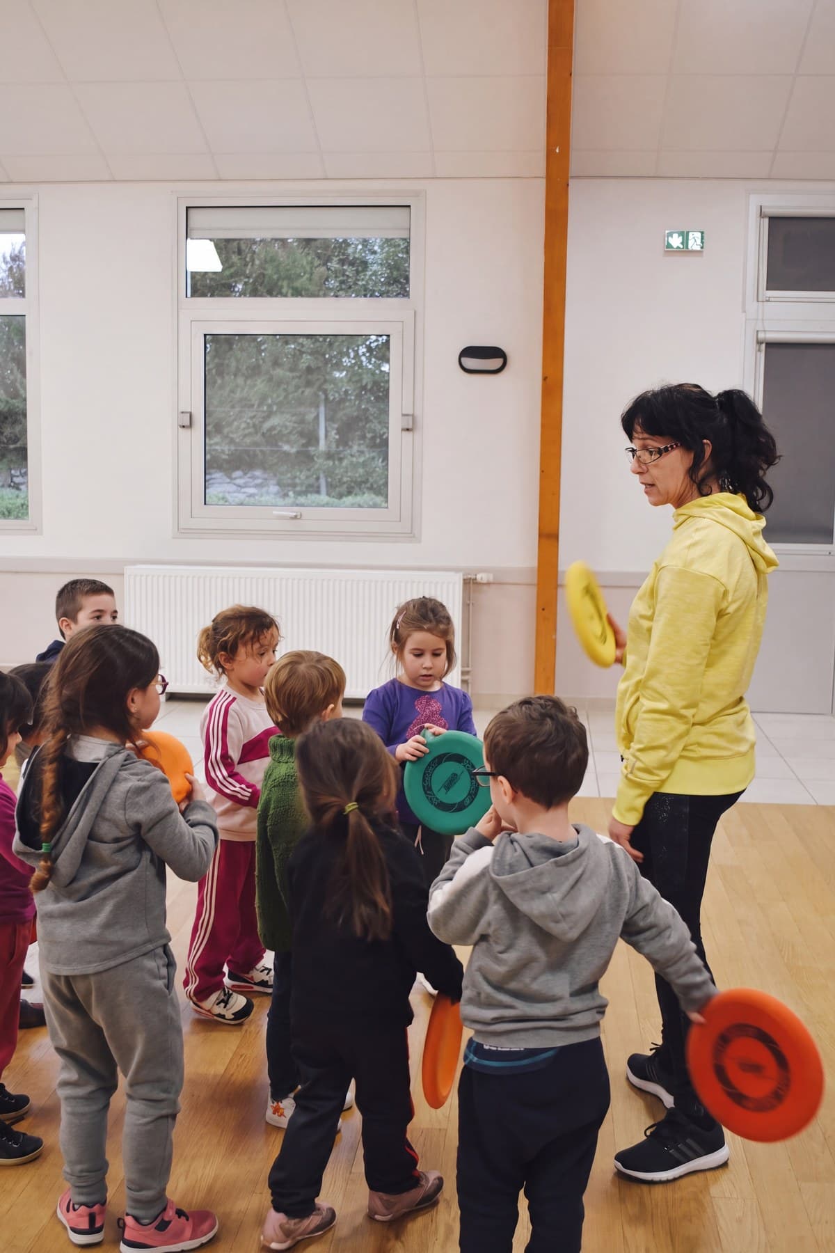 L’éducatrice explique la consigne au groupe d’enfants rassemblé devant elle.