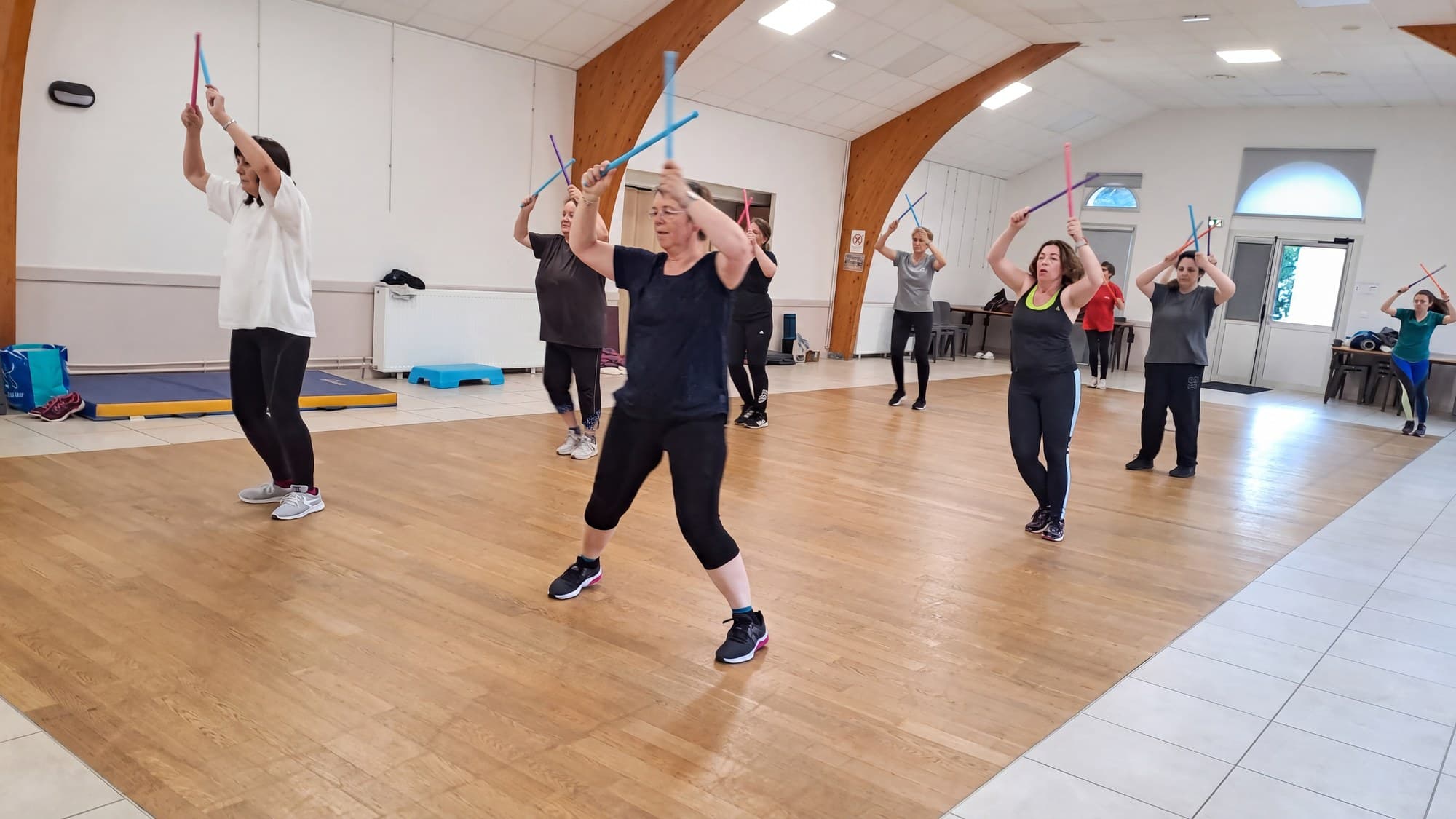 Groupe de fitness bras levés, bâtons croisés au-dessus de la tête.