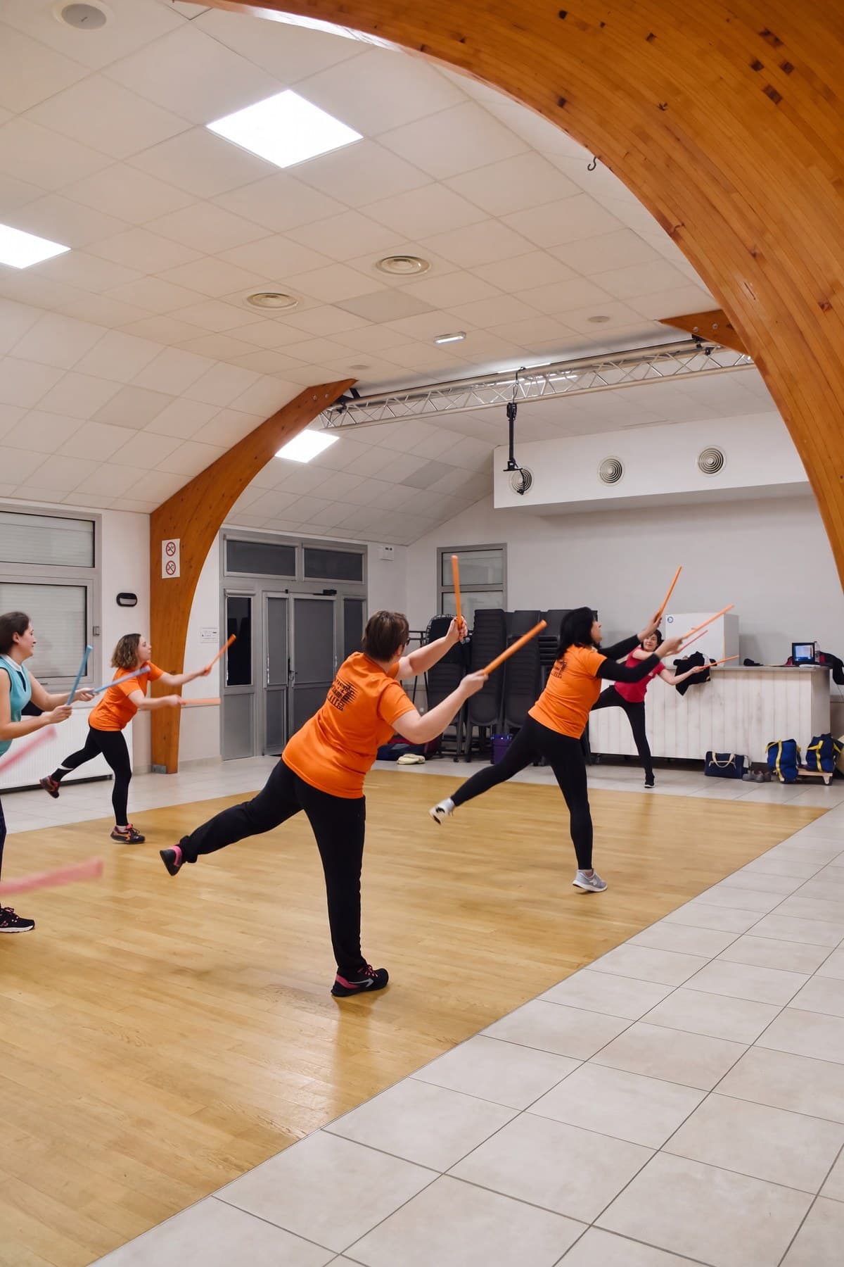 Deux adhérentes en maillot orange en pleine fente avec leurs bâtons.