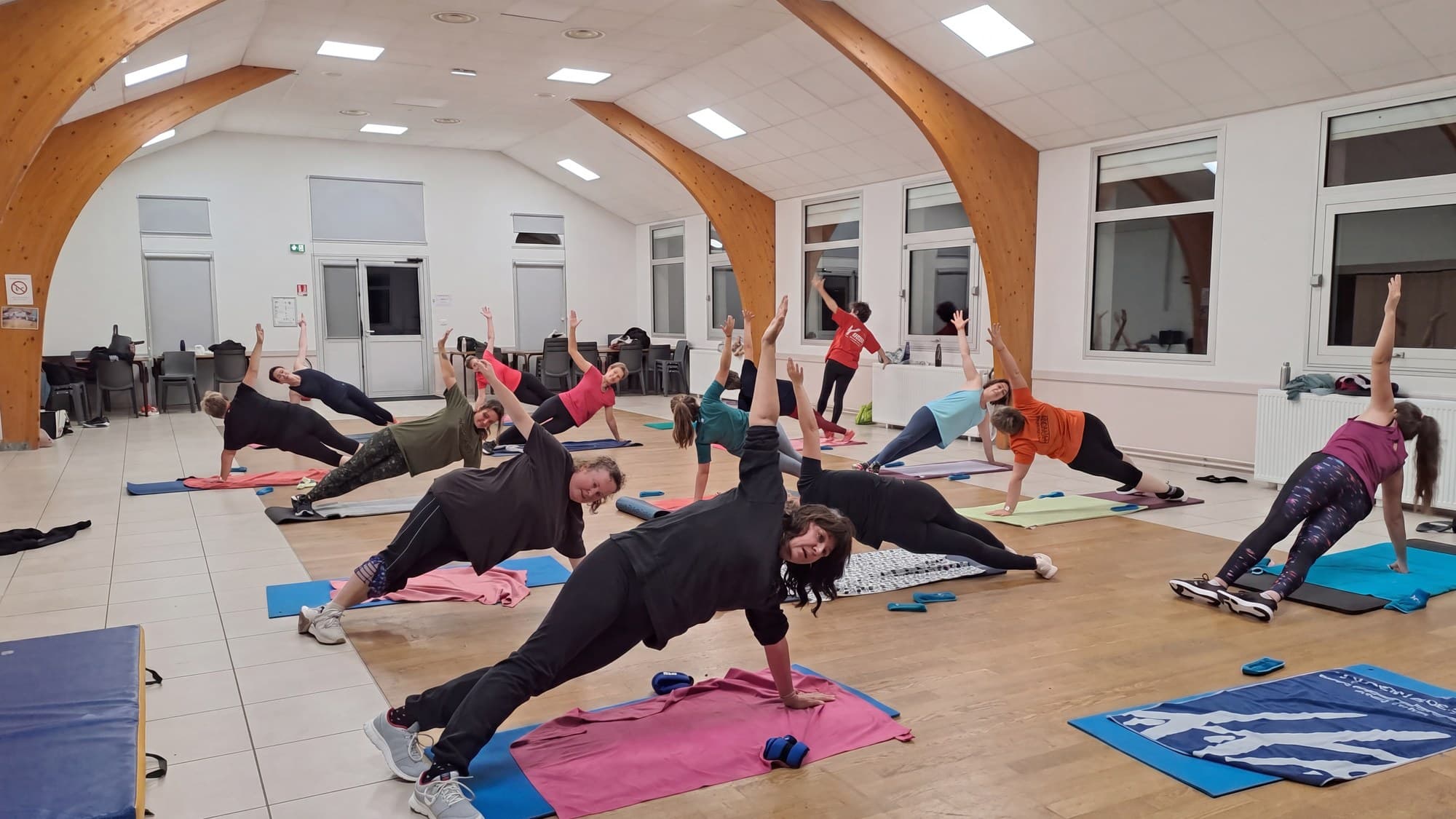 Salle pleine en gainage latéral pendant un cours de Pilates.