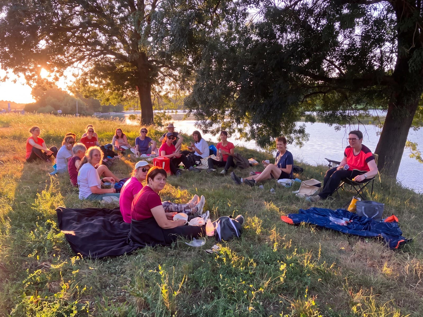 Le groupe du club assis dans l’herbe au bord de l’eau, au soleil couchant.