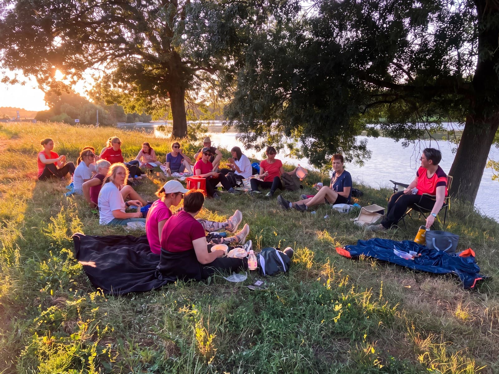 Adhérentes du club installées sur des couvertures, repas partagé au bord de l’eau.