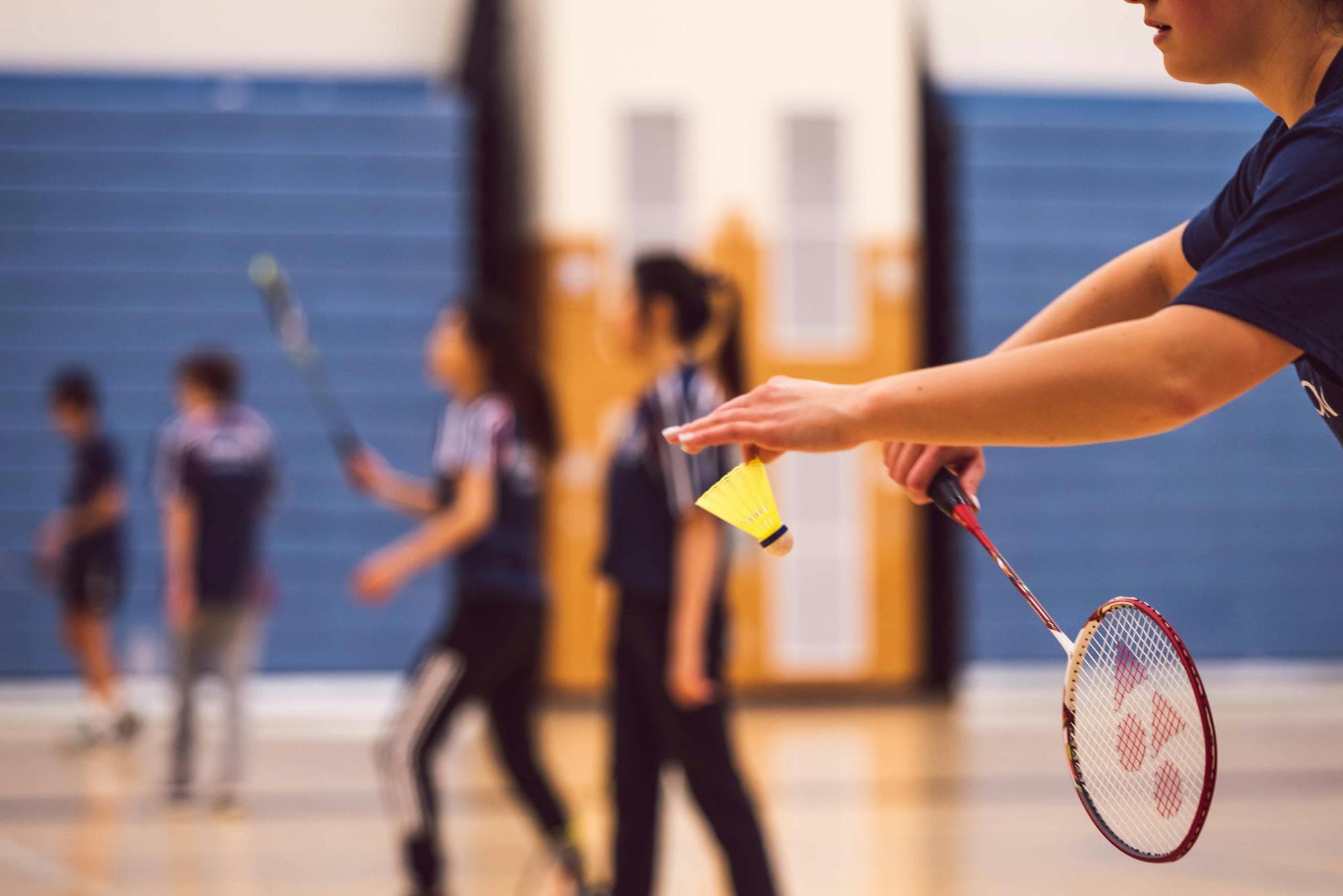 Échange de volants pendant une séance de badminton en gymnase.