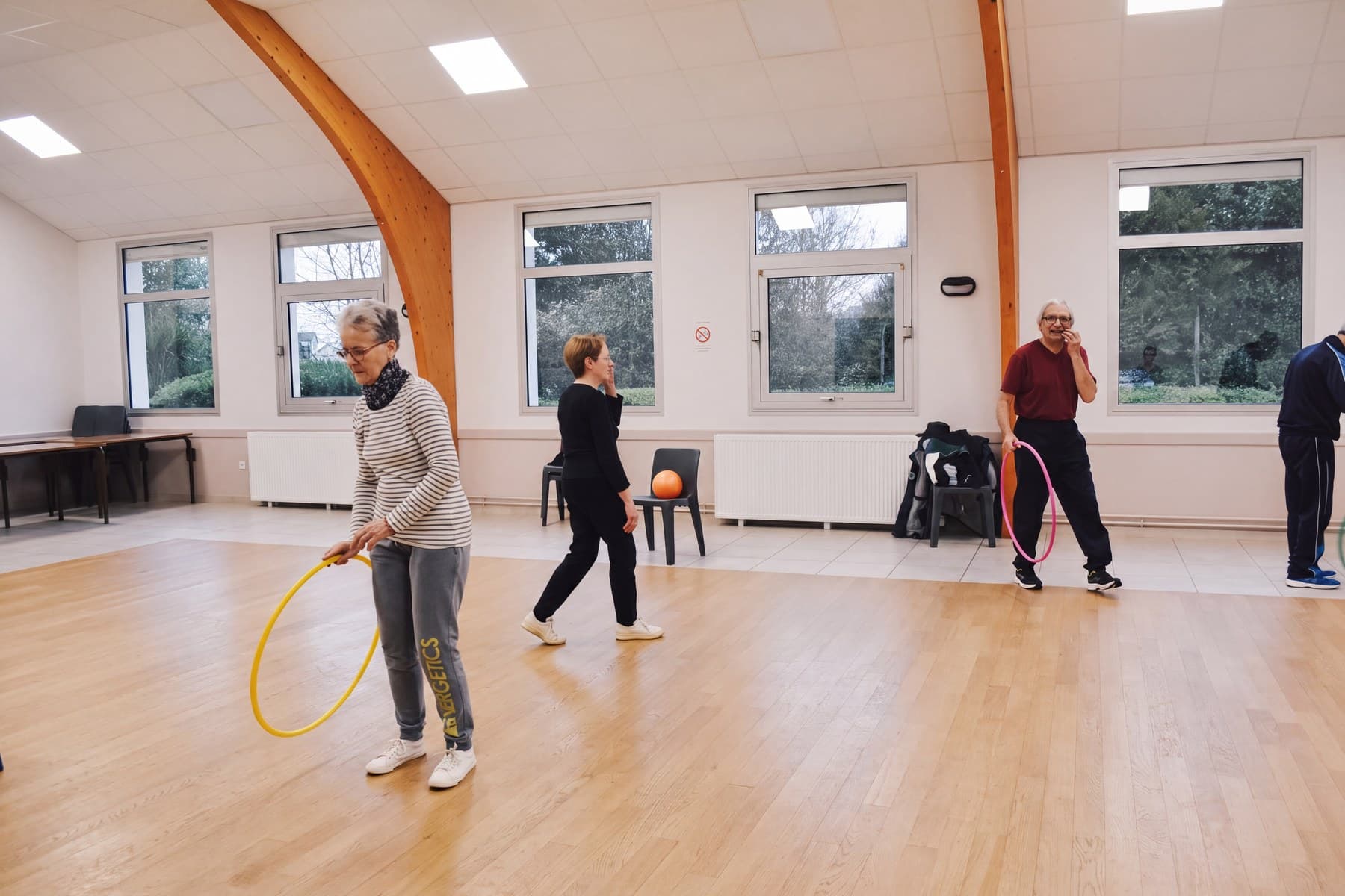 Séance Sport Santé Sénior dans la salle, une adhérente tient un cerceau jaune au premier plan.
