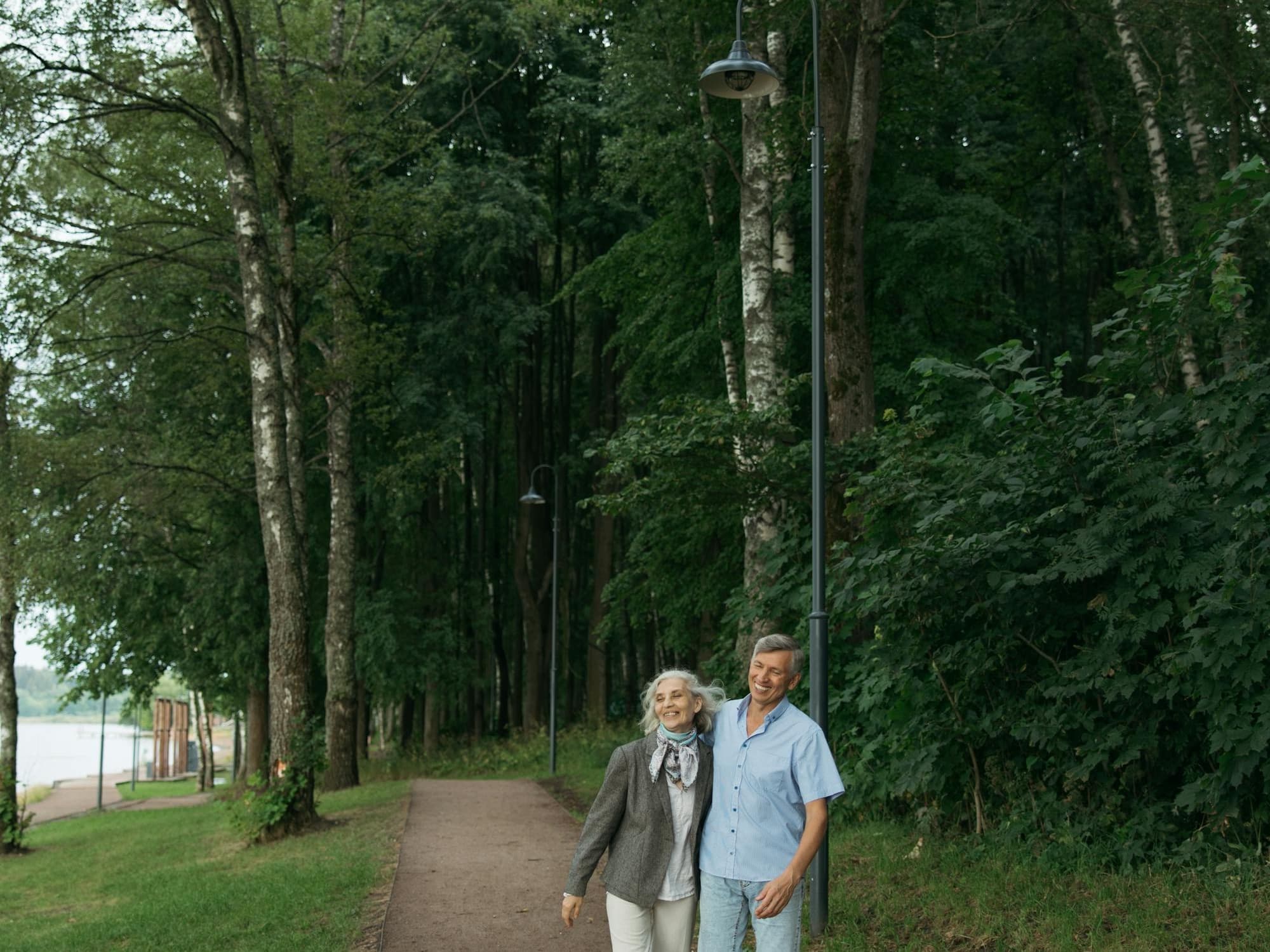 Couple senior en marche dans un parc verdoyant.