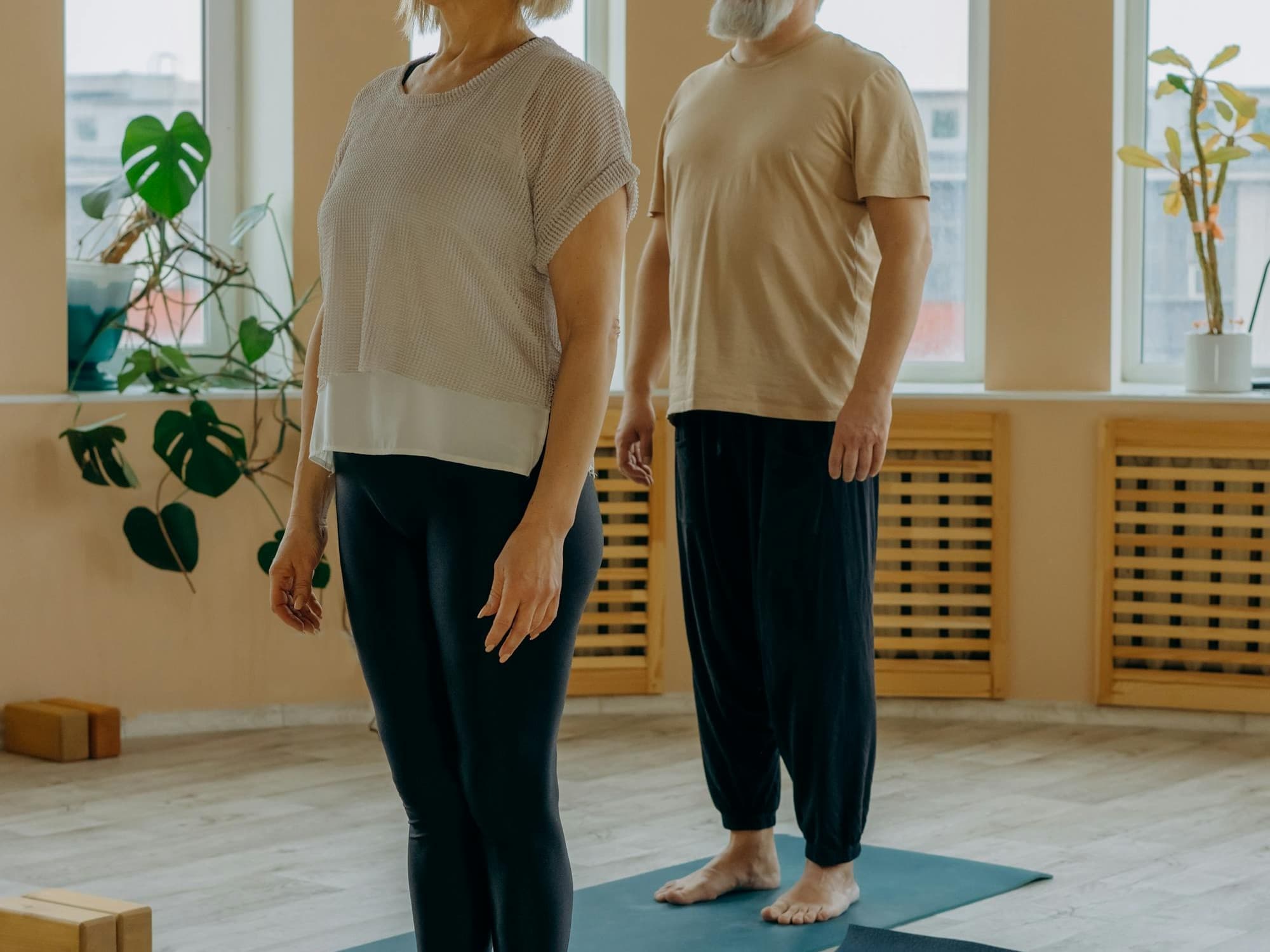 Couple senior debout sur tapis lors d'une séance Sport Santé en intérieur.